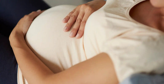 Femme enceinte de 5 mois caressant son ventre arrondi, dans un moment de tendresse