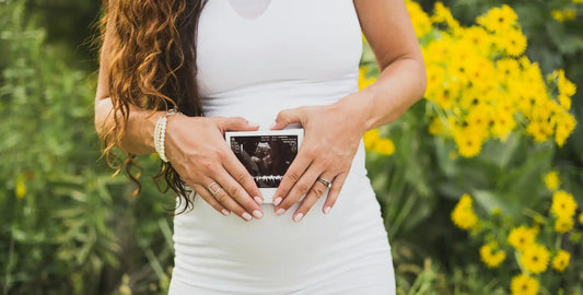 Femme enceinte de 8 mois portant les mains sur son ventre — phase avancée de grossesse