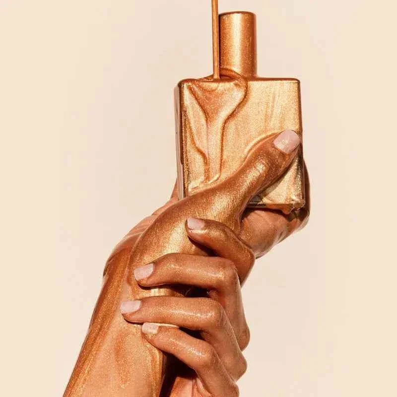 Flacon doré de parfum tenue par une main avec finition métallisée | La Para Du Lac